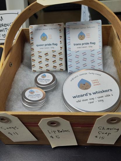 a basket with soaps and lip balms from tubby tabby soaps - labels below read Soaps $11 Lip Balms $5 and Shaving soaps $15