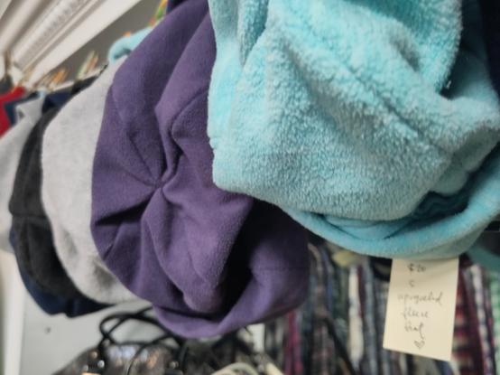 multicoloured upcycled hats hung on a string, label below reads $20 S upcycled fleece hat