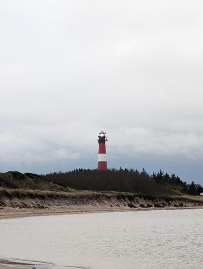 Küstenlandschaft mit Leuchtturm, viel Himmel, bewölkt