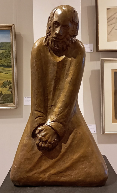 Bronzeplastik eines knienden Mannes, der die Arme mit gefalteten Händen vor dem Körper nach unten gestreckt hält.