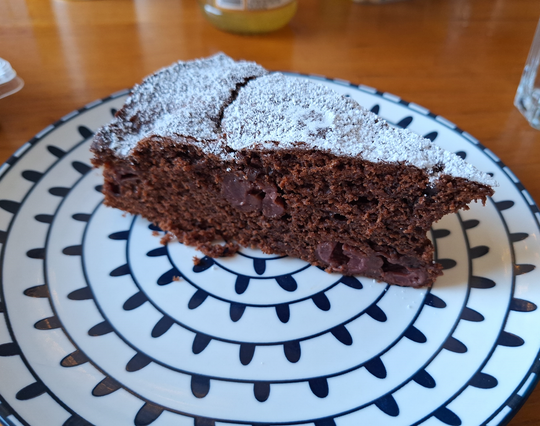 One piece of chocolate cherry cake on a plate. you can feel the fluffiness of the dough and juiciness of the cherries just by looking at it.