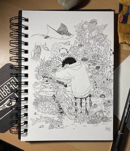 Picture of a sketchbook with a Black and white drawing showing a character sleeping on a desk surrounded by marine animals and algae