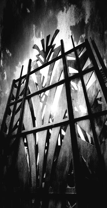 Low-angle, black and white photograph of an abstract metal structure with geometric cutouts against a dramatic sky, with the sun shining brightly through the open spaces.