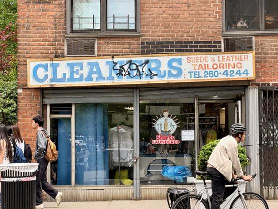 A hand-painted sign: "Cleaners / Suede & leather / Tailoring / Tel: 260-4244"