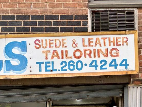 Detail of a hand-painted sign: "Suede & leather / Tailoring / Tel: 260-4244"