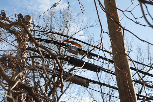 A squirrel runs along power lines. The photo is captured with the squirrel in mid jump.