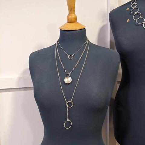 A selection of LollaMac silver necklaces displayed on a black mannequin