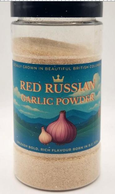 A large image of a small jar filled with a light-brown powder and bearing a label that shows blue hills and a large bulb of red garlic. At the top of the label is "Locally grown in beautiful British Columbia," then beneath that, in large letters, "Red Russian / Garlic Powder."
