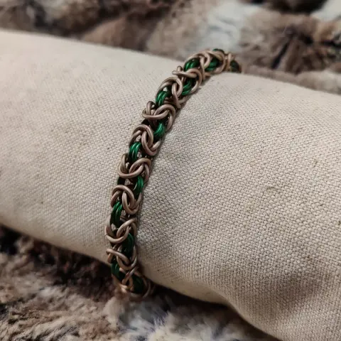 Bracelet en maille byzantine dans des couleurs naturelles : majoritairement taupe, et avec du vert foncé pour contraster.