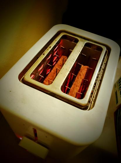 Filaments glow red as toast toasts in the toaster, round side down.
