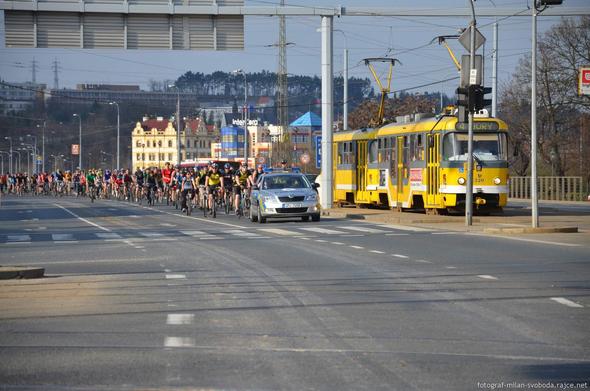 Strudel of cyclists with police car in front.