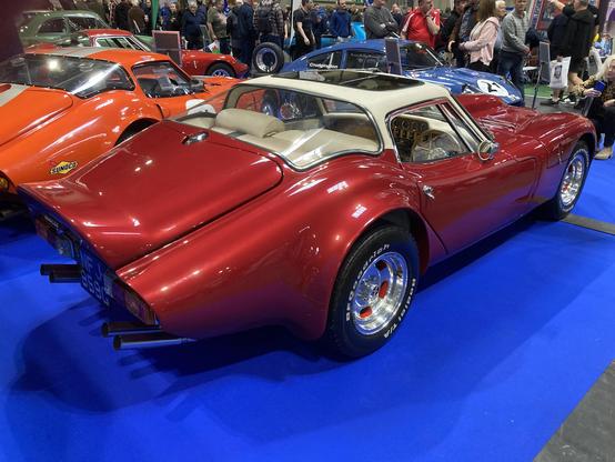 Red metallic Marcos V6 GT with white roof, rear quarter view