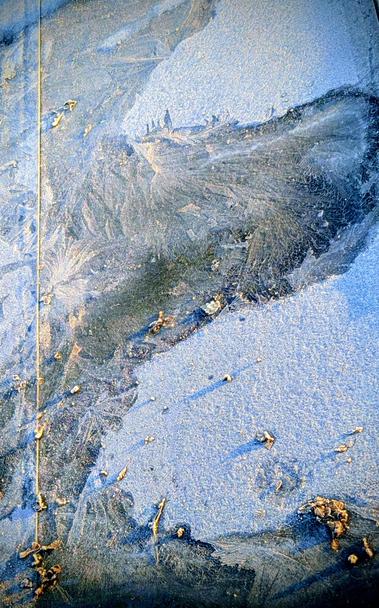 A frozen flat roof landscape. Hard side 
light creating shadows of the small debris scattered on the surface.