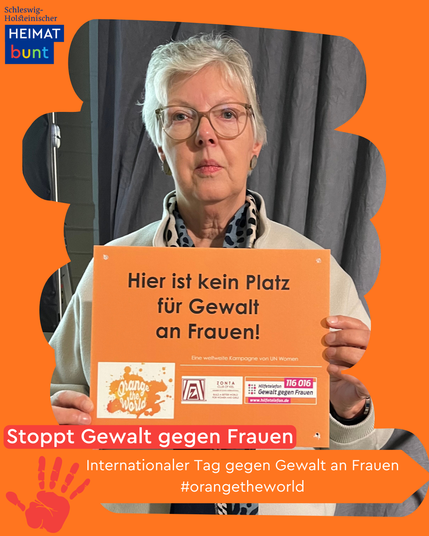 Frau hält oranges Schild mit Aufschrift "Hier ist kein Platz für Gewalt an Frauen"