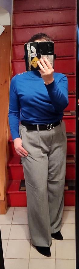 Blue sweater with gold buttons on the shoulder. Light grey wide-leg knit trousers. Black suede ankle boots, black belt with silver circle hardware.