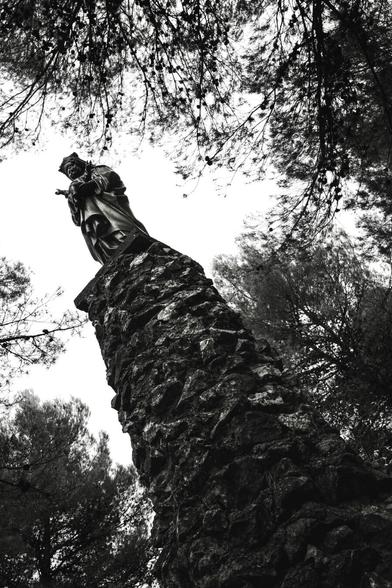 A statue of the Virgin Mary holding the infant Jesus in her arms, backlit and from a low angle.