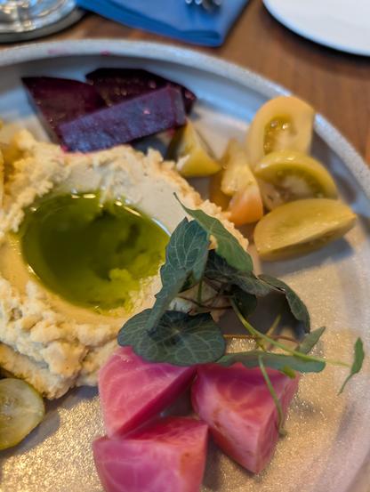 Vorspeisenteller mit verschiedenen Gemüsen, Kapuzinerkresse und Hummus mit Olivenöl