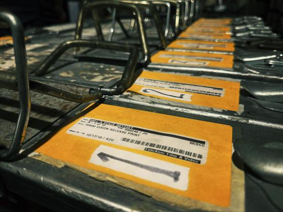 Large film canisters, each labeled a number from "1" to "10," sit on a small cart in a film storage room of the Hollywood Theatre, with one of the reels being held for the camera.