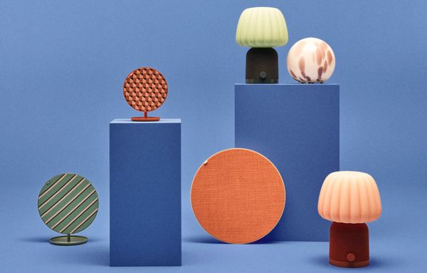 Un ensemble de haut-parleurs et lampes colorés de la collection Teklan d'IKEA, exposés sur des socles bleus.