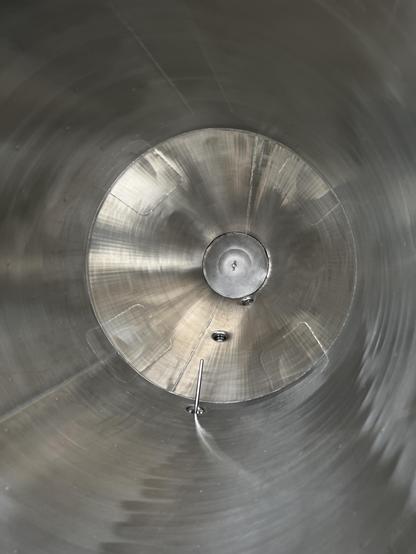 Shiny stainless steel fills the frame as we peer down into the cylindrical conical interior. As the vessel has aged it has developed subtle warping and distortion of the metal which has become rather interesting looking. There’s a mesh false bottom and some temperature probes visible.