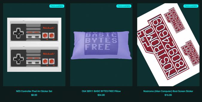 Screenshot of the store showing three articles:
A pixel-art recreation of the NES controller as sticker;
A Commodore 64-inspired throw pillow in the signature blue reading 38911 BASIC BYTES FREE;
A set of stickers depicting the Nostromo boot screen as seen in "Alien"