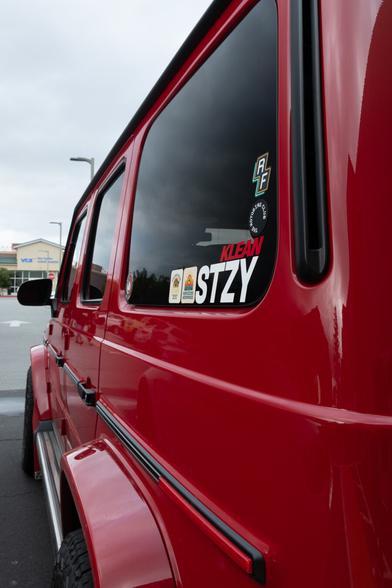 A red boxy SUV, photographed obliquely by its rear pillar, looking down its side.