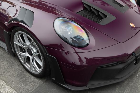 Front end detail of an exotic sports coupe in a purple shade.
