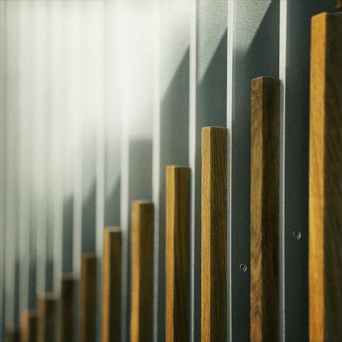 Thin, vertical wooden beams screwed to silver metal supports ascend through the frame from left to right.