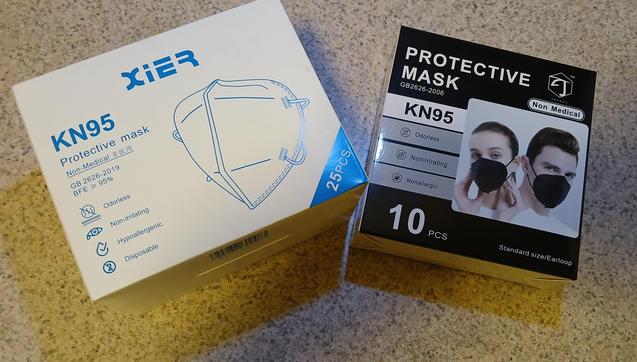 Two boxes of KN95 masks.
The first box is white, with the name XiER and a line drawing of a mask
KN95
Protective Mask
Non-Medical [three Chinese characters]
GB2626-2019
BFE >= 95%
Odorless, Non-irritating, Hypoallergenic, Disposable
25 pcs

The second box is black, with the name Zhongji and a photo of two white people with dark hair posing with black masks on
Protective Mask
Non-Medical
GB2626-2006
KN95
Odorless, Non-irritating, Hypoallergenic
10 pcs
Standard size/Earloop