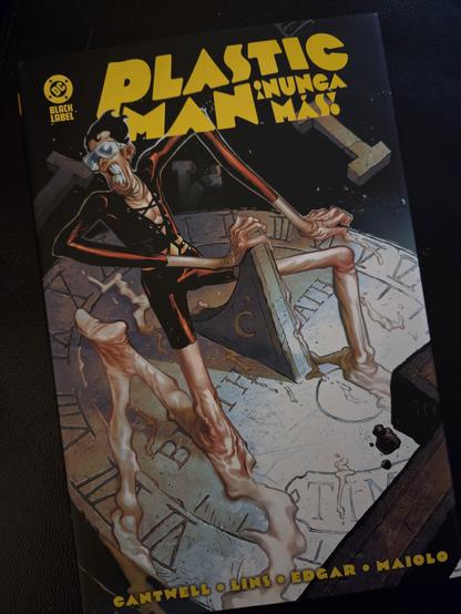 Portada de Plastic Man ¡Nunca más! Se trata de un dibujo en un estilo feísta y desasosegante donde vemos a Plastic Man (un hombre enjuto vestido con un body de lycra granate) arrodillado sobre un reloj de sol. El cuerpo, de plástico, se está derritiendo desde las piernas sobre el reloj mientras la cara del personaje muestra terror ante esta situación