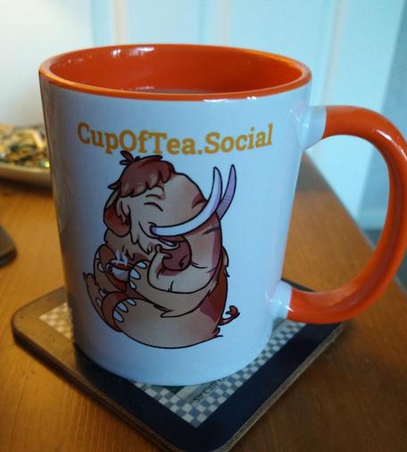 Orange cupofteasocial mug on a bedside cabinet