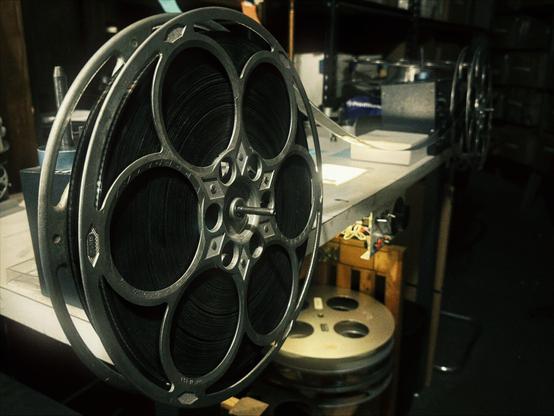 Multiple photos of the Hollywood Theatre archive display movie posters, film reels, a splicing table, and a giant sign that reads, "BEN HUR."