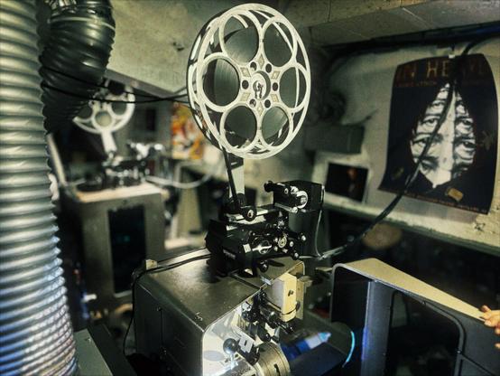 Multiple photos of the Hollywood Theatre archive display movie posters, film reels, a splicing table, and a giant sign that reads, "BEN HUR."