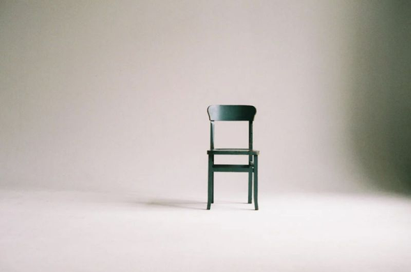 Image of empty green chair against white wall. Image by Paula Schmidt via Pexels