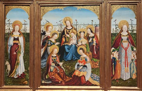 Rectangular triptych with a large panel at center depicting the Virgin holding baby Jesus and surrounded by six female saints, their names inscribed in their halos. The left small panel depicts a female saint with a small lamb on a leash, and the right panel has a full-sized female saint surrounded by smaller (adult) women, i.e. her devotees. Together the panels form a continuous scene of all of the aforementioned women gathered in a field or garden with a fence and birds in the background.