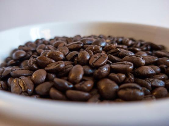 A color photo showing coffee beans in a white bowl.