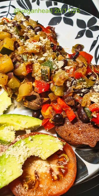 A plate of Goodstore 'Vegan Tender Steak',  Baked Sweet Potato topped with Stir Fried Vegetables, served with Fresh Avocado & Tomato. Topped w/ Yeast Flakes.
