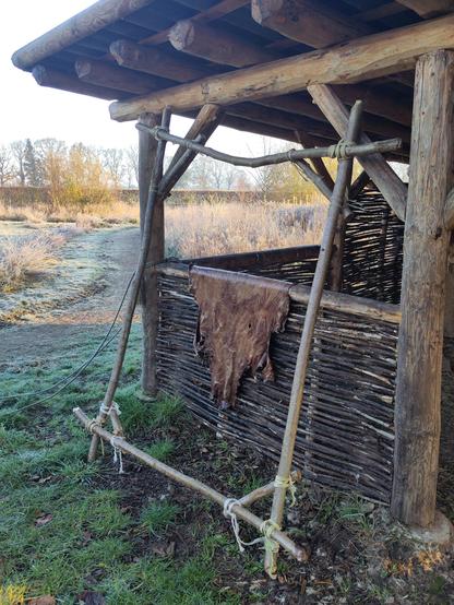 De huid die kletsnat hangt over een randje, met een houten rek ervoor. Klaar om opgespannen te worden.