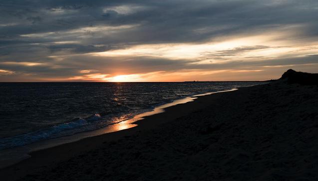 Dramatic sunset on Cape Cod's Herring Cove Beach as darkness falls
