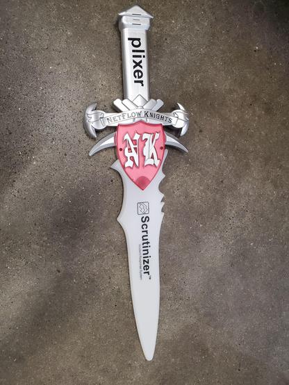An elaborate toy sword plastered with corporate names on it: Plixier on the hilt, Netflow Knights on the cross guard, and Scrutinizer on the faux blade