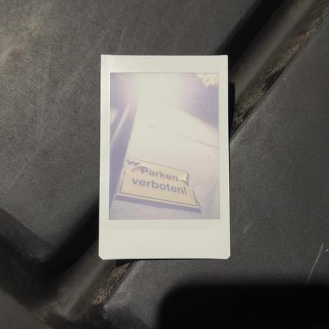 Instant photo of an warning sign below a lantern on gray plastic shape.