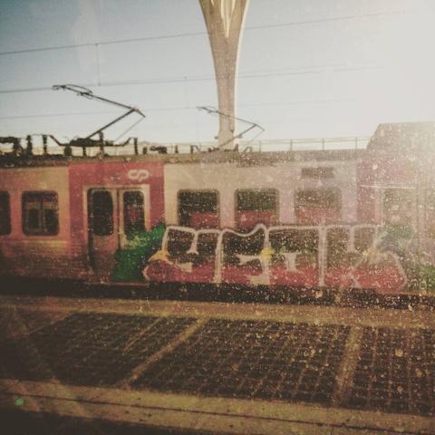 a grafittied train is seen from another dirty train window