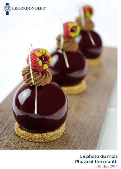 A single raspberry sits atop a sphere of chocolate containing a chocolate praline, based with a light shortbread.