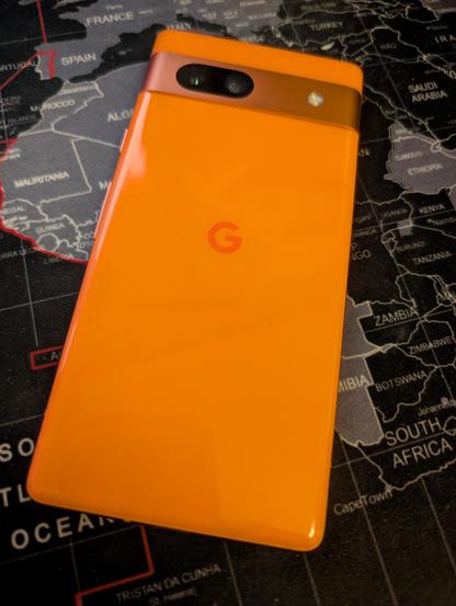 Back view of the Google Pixel 7a with a camera bar containing the dual cameras and an LED flash. The Coral (orange) is an exclusive colour option from Google stores in the US.
