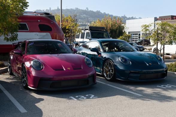 Two sports coupes, one in a purplish-red tint, and one in dark teal.