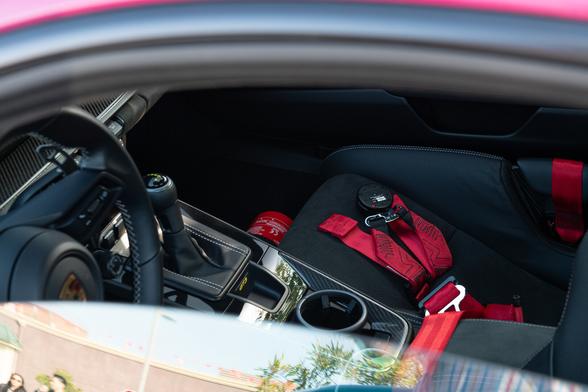 Interior shot showing a black interior with carbon fiber inserts, and red racing harnesses.