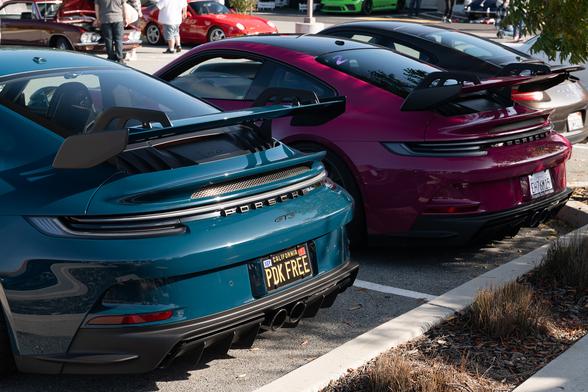 Two sports coupes, one in a purplish-red tint, and one in dark teal.