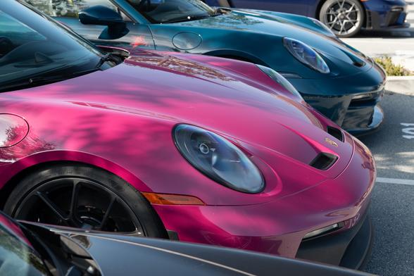 Two sports coupes, one in a purplish-red tint, and one in dark teal.