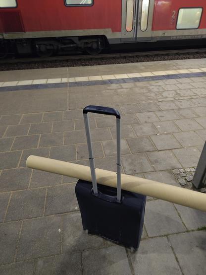 Rollkoffer mit Posterrolle am Bahnsteig