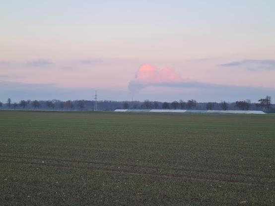 Dampfsäule eines Kraftwerks in der Ferne.
Oben sieht man rotes licht, unten ist sie schon dunkel